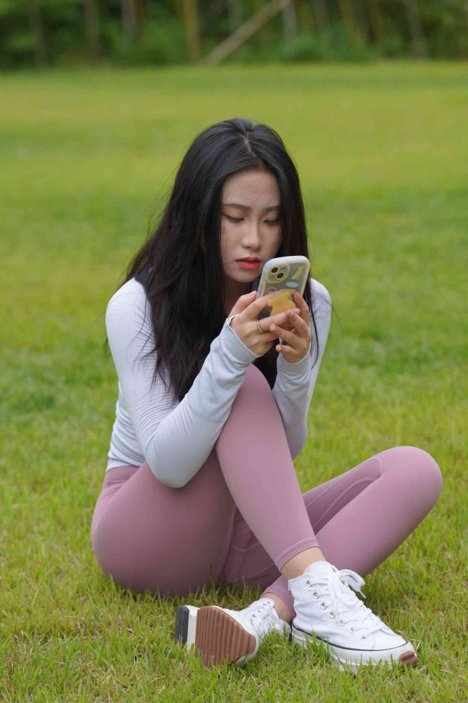 图片[1]-坐在草地玩手机的瑜伽姑娘【733P】04012-禾野套图